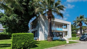 A modern two-story building with a sign reading "ACCUEIL" on the ground floor, surrounded by well-maintained greenery and palm trees. - Carre Marine N°105 - 3P6 (Mandelieu-la-Napoule)