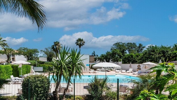 A pool area with lounge chairs and umbrellas, surrounded by greenery and a clear sky. - Carre Marine N°105 - 3P6 (Mandelieu-la-Napoule)