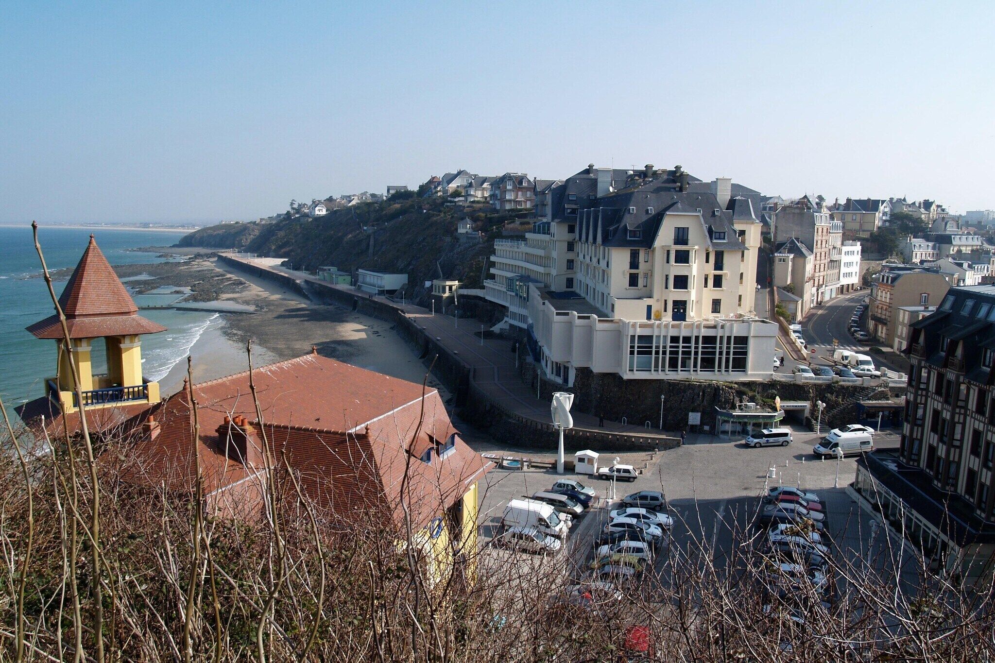 Une ville côtière avec une plage, des bâtiments et des voitures garées.