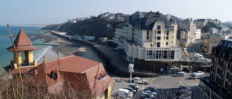 Une ville côtière avec une plage, des bâtiments et des voitures garées.