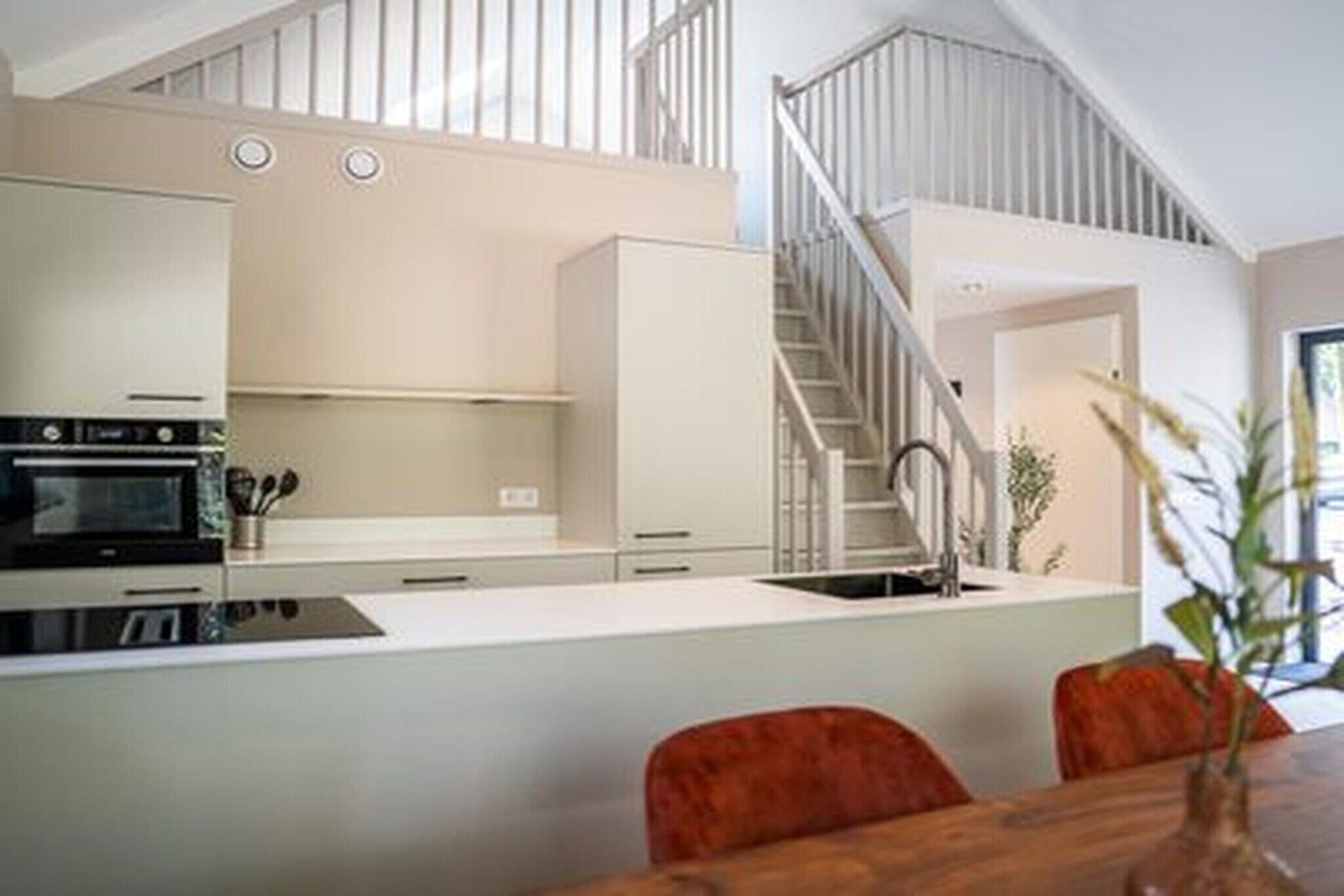 A modern kitchen with white cabinets, a stainless steel range hood, and a central island.