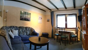 Uma sala de estar com sofá, mesa de centro e área de jantar com cadeiras e mesa.