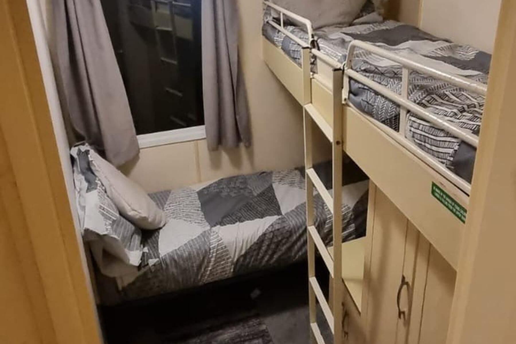 Une petite pièce, de taille modeste, équipée d’un lit superposé et d’un lit simple.