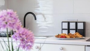 A modern kitchen with a black faucet, white cabinets, and a plate of croissants on the counter. - New! Delightful 2BR Flat in Woolwich (Greater London)
