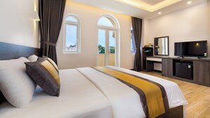 Camera d'albergo con un letto grande, televisione, mini-frigo e vista sull'esterno attraverso le finestre.