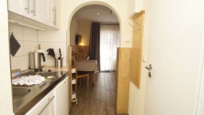 Une cuisine étroite avec un coin repas, un plancher en bois et une vue dégagée sur l’espace adjacent, accessible par une arche.