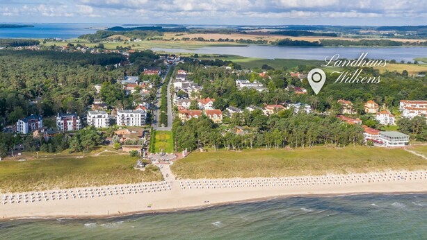 Vue aérienne d’une ville côtière avec une plage, des immeubles résidentiels et une vaste étendue d’eau.