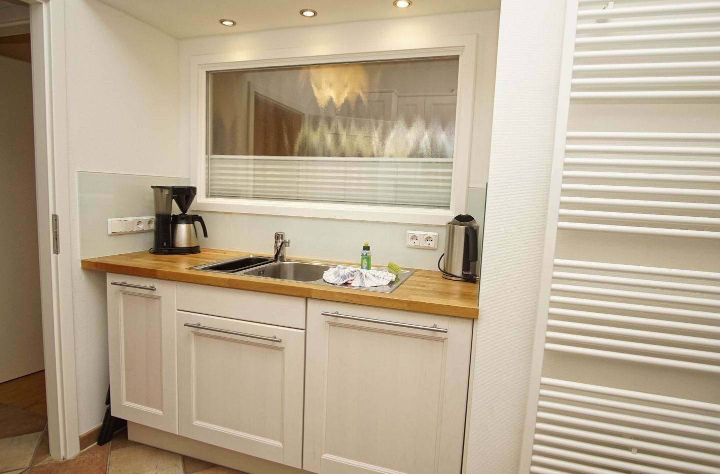 A compact kitchen with a sink, countertop, and cabinets.