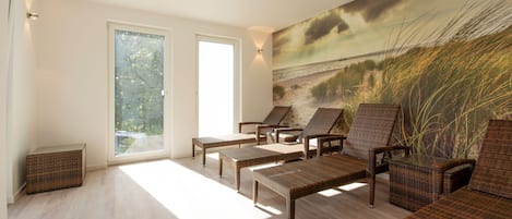 A sunlit room with wicker furniture, large windows, and a beach mural.