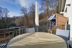Une terrasse extérieure circulaire, dotée d’une rambarde, d’une chaise en osier et d’un parasol blanc.