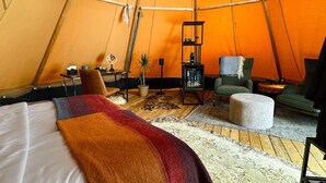 Ein Zelt mit Bett, Stuhl, Tisch und einem kleinen Regal.