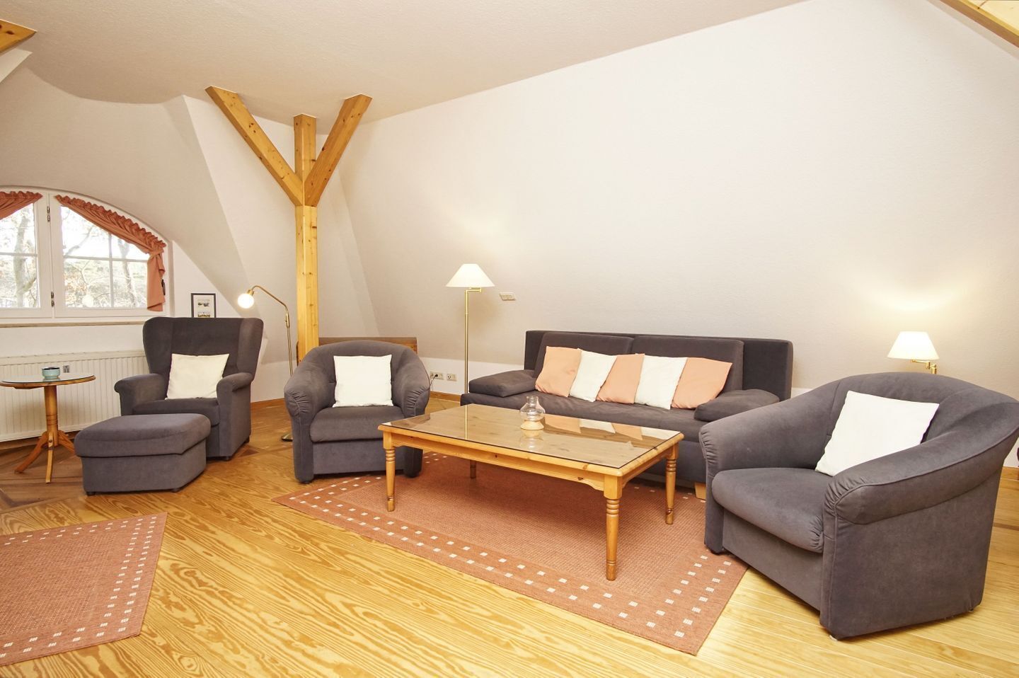 A cozy living room with a sofa set, armchairs, a coffee table, and a lamp.