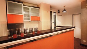 A kitchen with a black countertop, orange cabinetry, and a microwave. - Standard 1-bedroom apartment in Strong Center of Belgrade with Private Garage (Beograd)