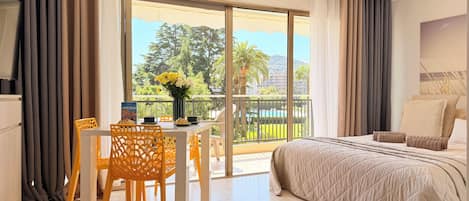 Een hotelkamer met balkon, een bed, een eettafel met stoelen en uitzicht op het omliggende landschap.