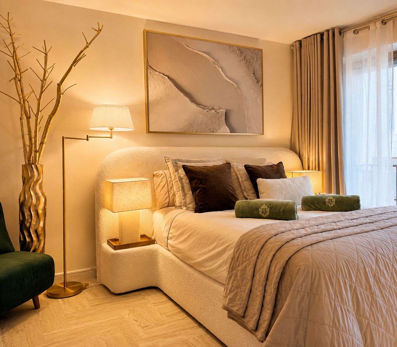 Een moderne slaapkamer met een gebogen bed, bedlampen, een decoratieve vaas en een groot abstract schilderij.