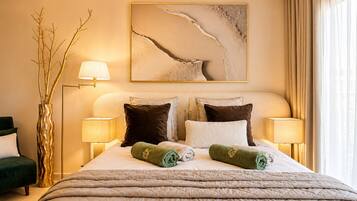 Une chambre d’hôtel avec un lit, deux tables de chevet avec des lampes, une lampe sur pied, un tableau au mur et une fenêtre avec des rideaux.