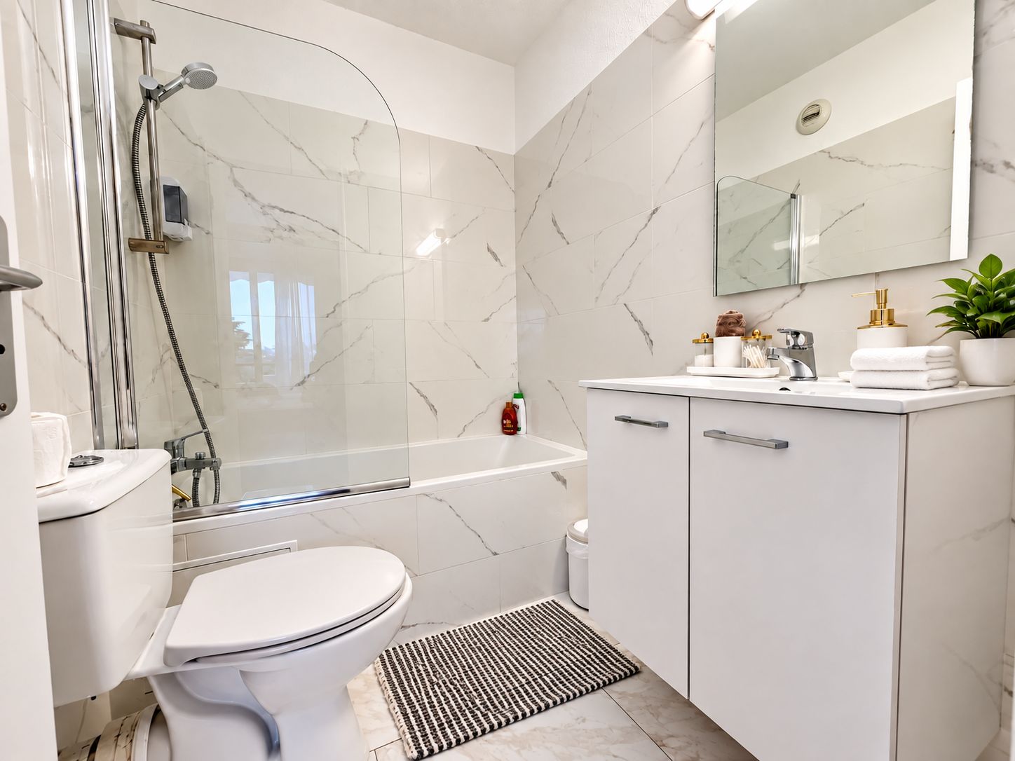 A modern bathroom with a shower, toilet, and sink.