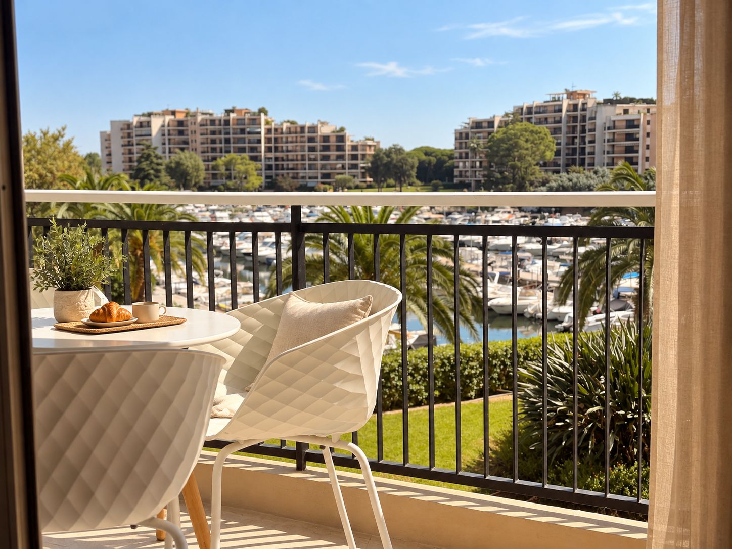 A balcony with a table, chairs, and a view of a marina and buildings.