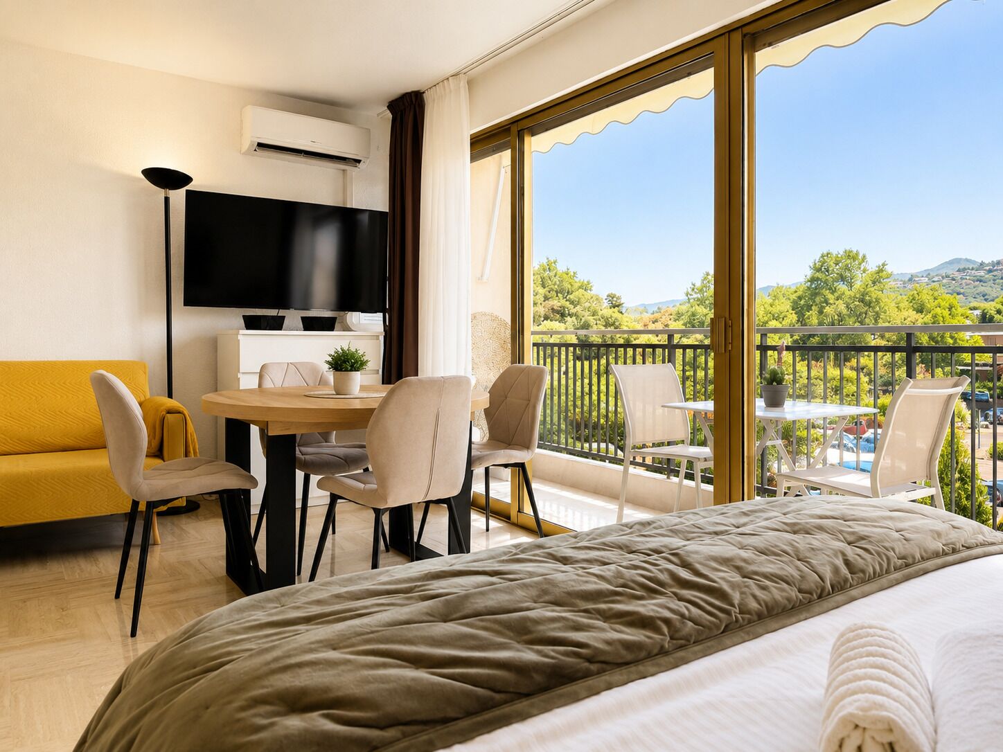 Ein Hotelzimmer mit einem Bett, einem Fernseher, einem Esstisch mit Stühlen, einer Couch und einem Balkon mit Blick.