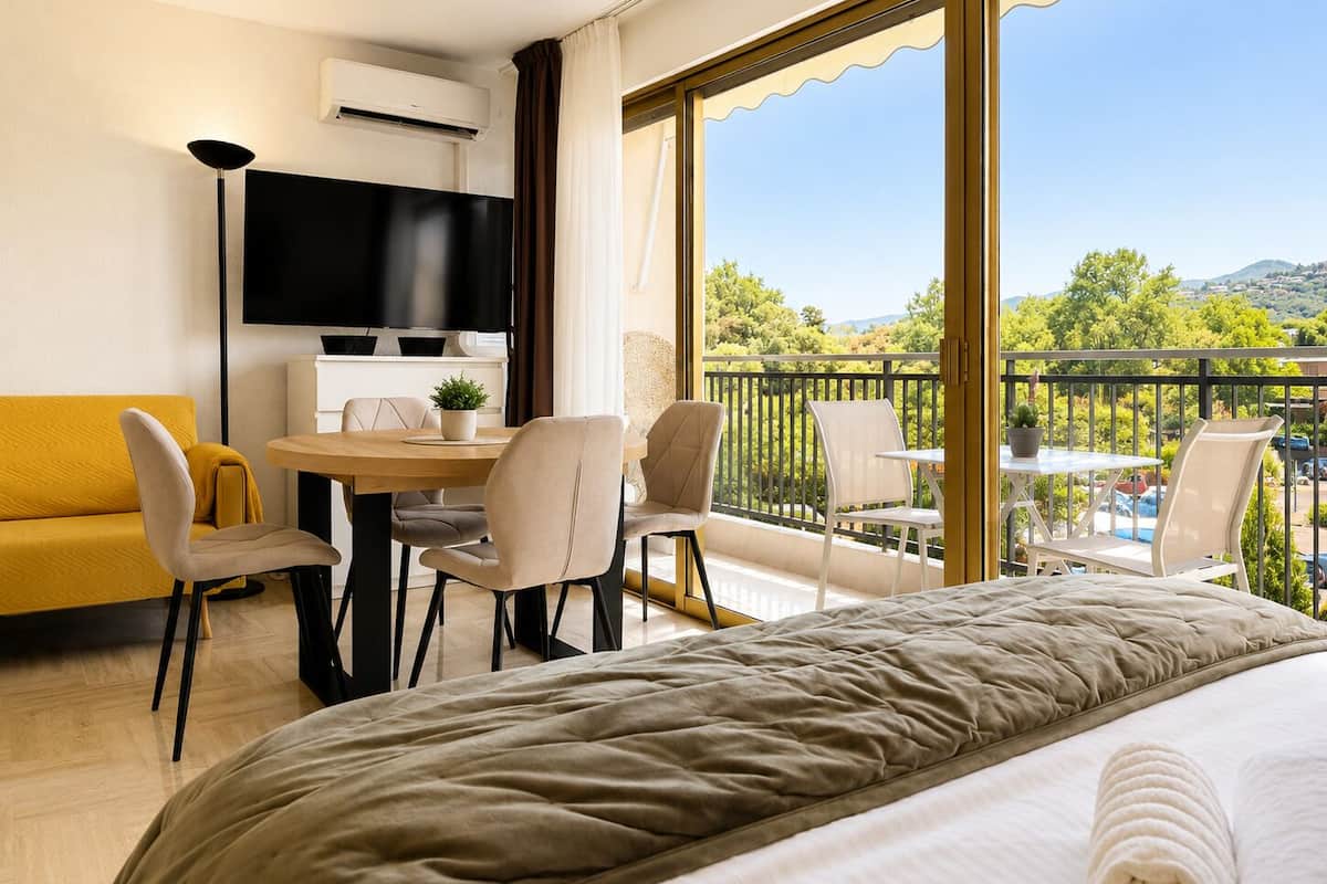 Ein Hotelzimmer mit einem Bett, einem Fernseher, einem Esstisch mit Stühlen, einer Couch und einem Balkon mit Blick.