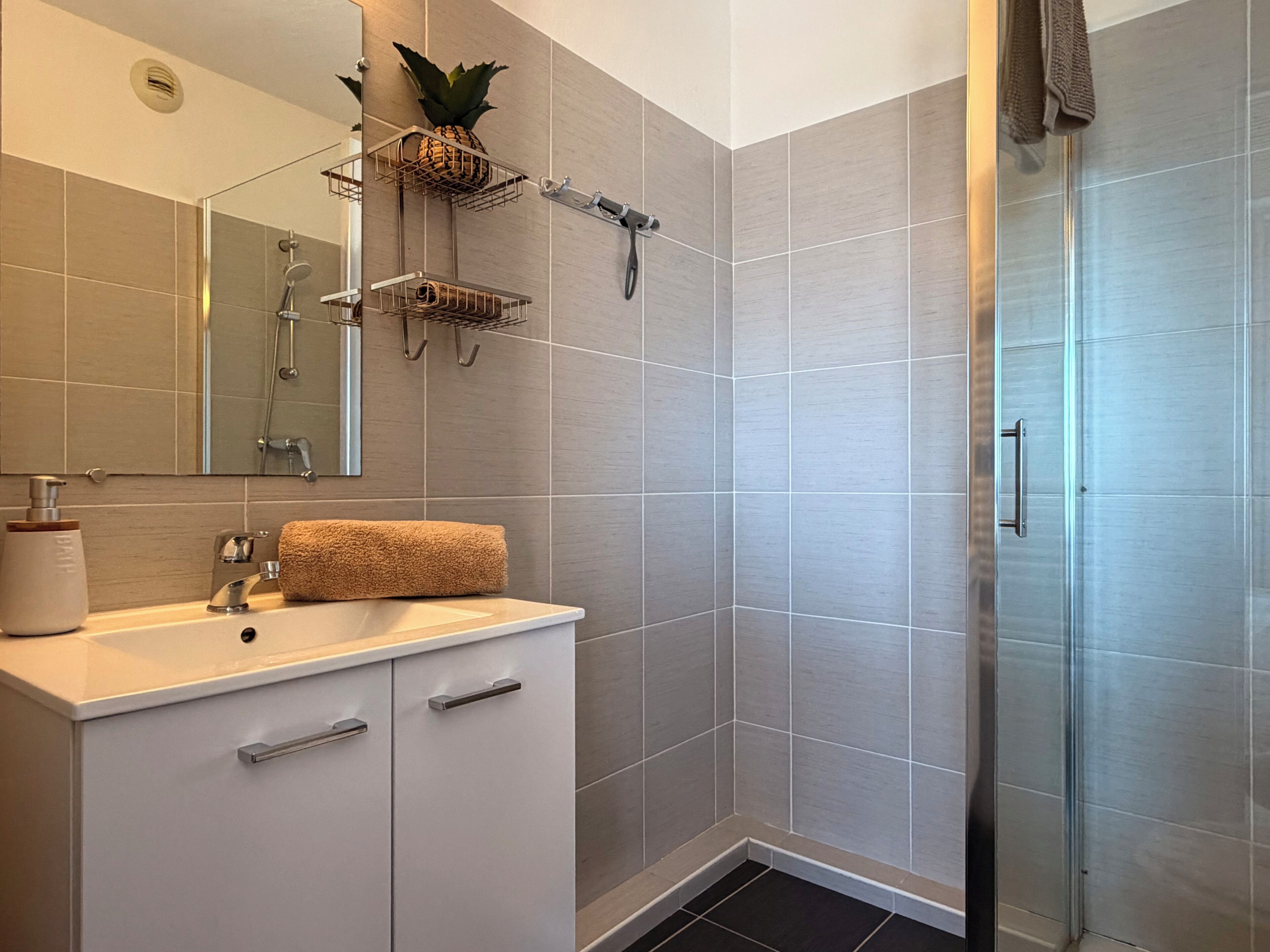 A modern bathroom with a shower, a sink with a towel, and a mirror.