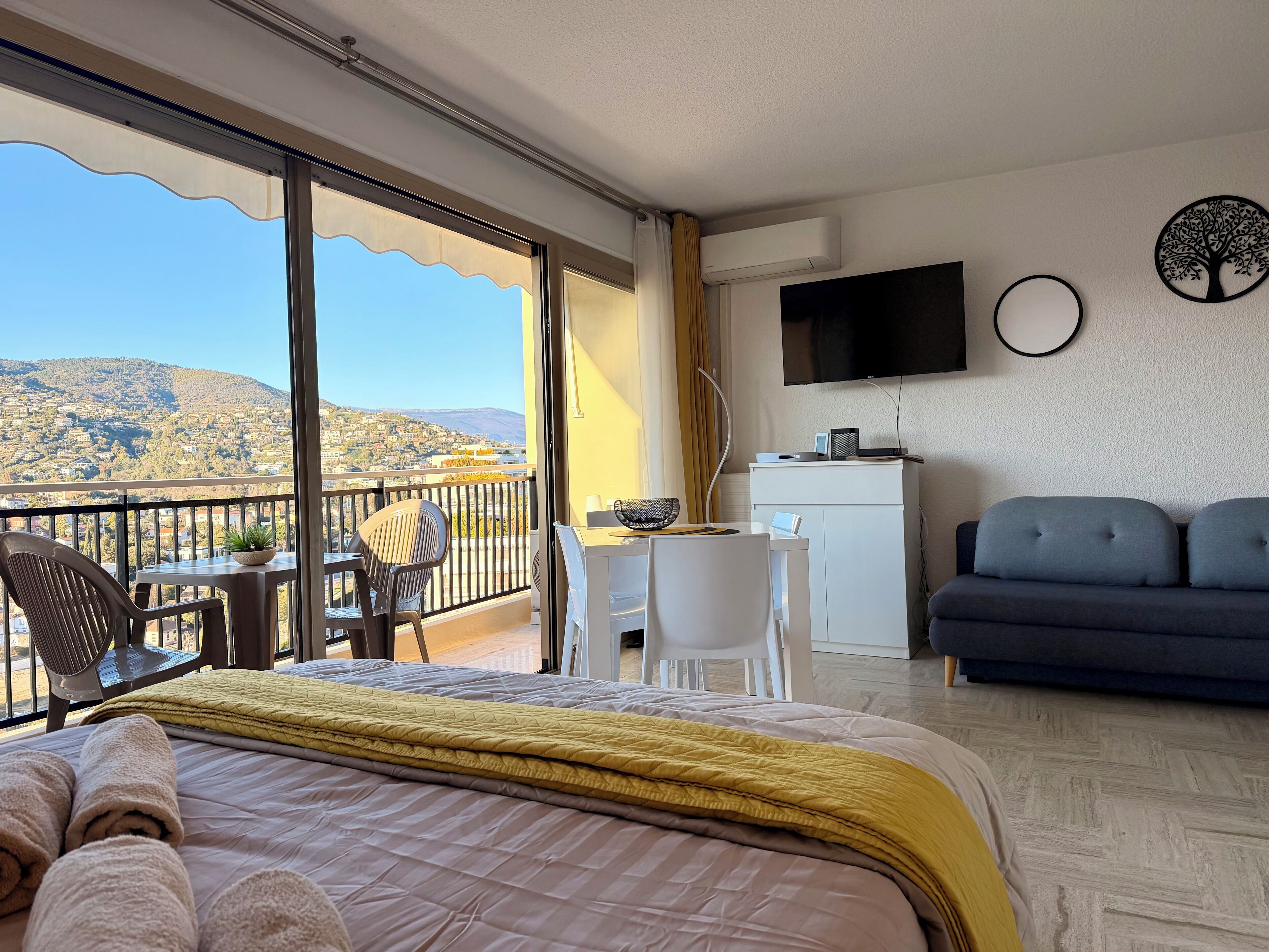 Une chambre d’hôtel comprenant un lit, un bureau, un canapé, une télévision et un balcon avec vue sur la ville.