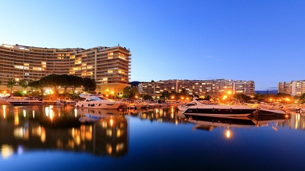 Un puerto deportivo con barcos y un hotel grande con varios balcones.