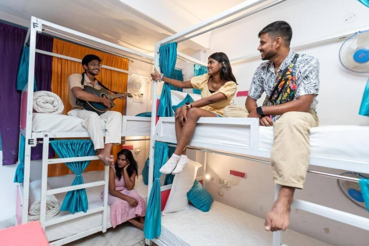 A dormitory room with bunk beds, a fan, and curtains.