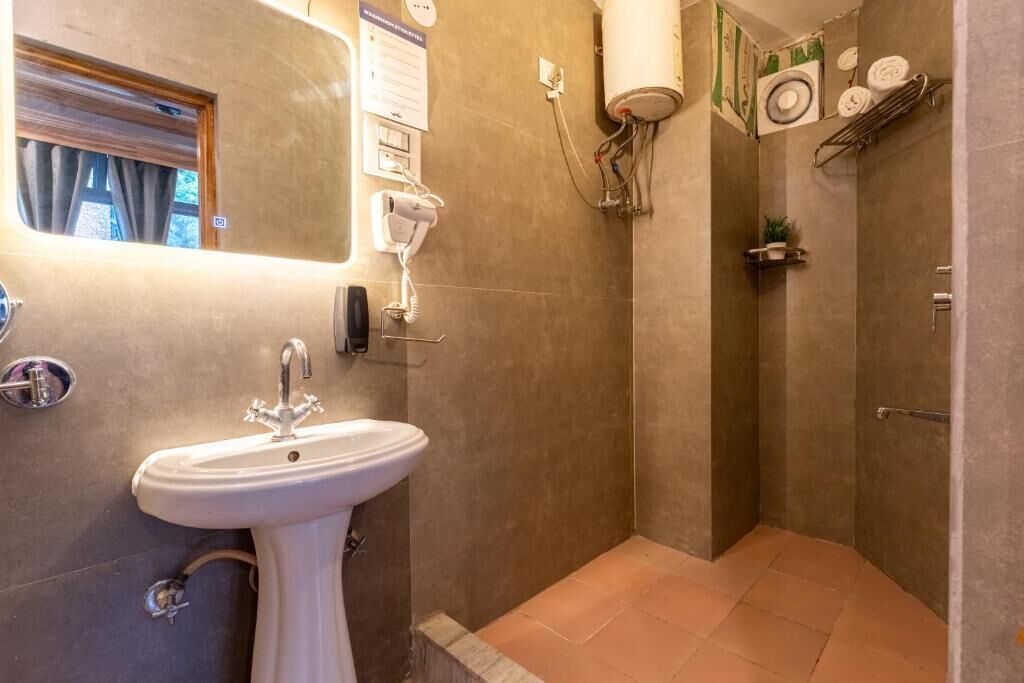 Een badkamer met een wastafel op een voetstuk, een douche en een handdoekhouder.