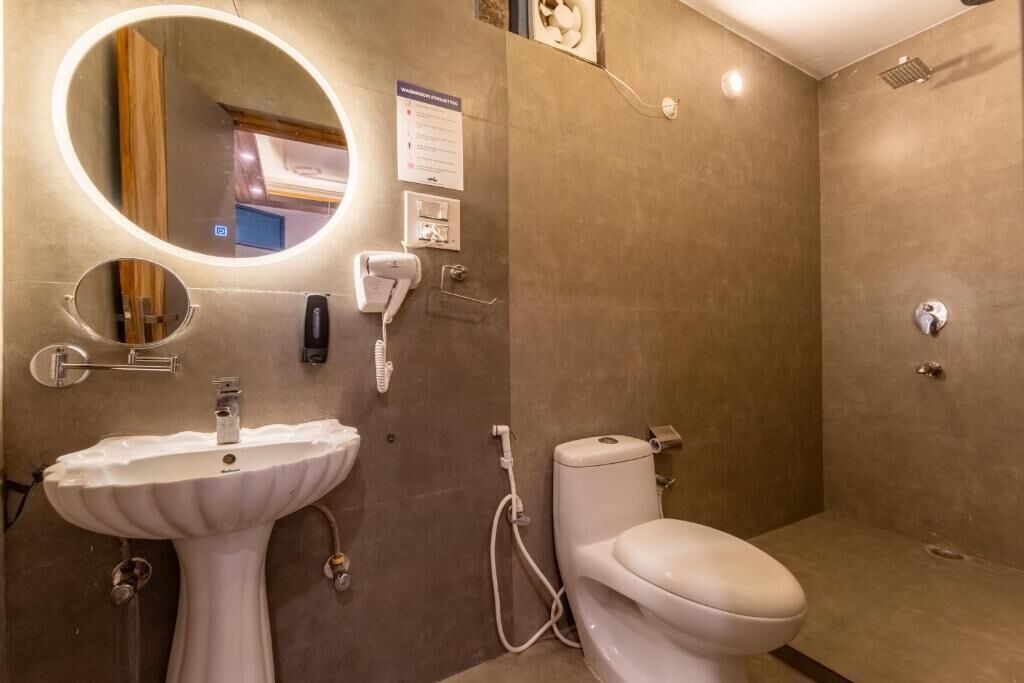 A bathroom with a pedestal sink, a toilet, and a shower.
