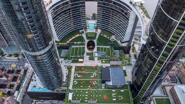 A high-rise building with a curved central atrium, surrounded by greenery and a river. - Skyscraper Cinema - Dream a thousand city lights (Brisbane City)