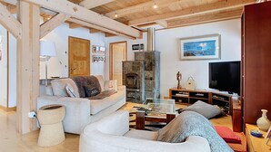A living room with a fireplace, a sofa, a television, and a coffee table. - 2 CHALET - Spacieux chalet au calme (Praz-sur-Arly)