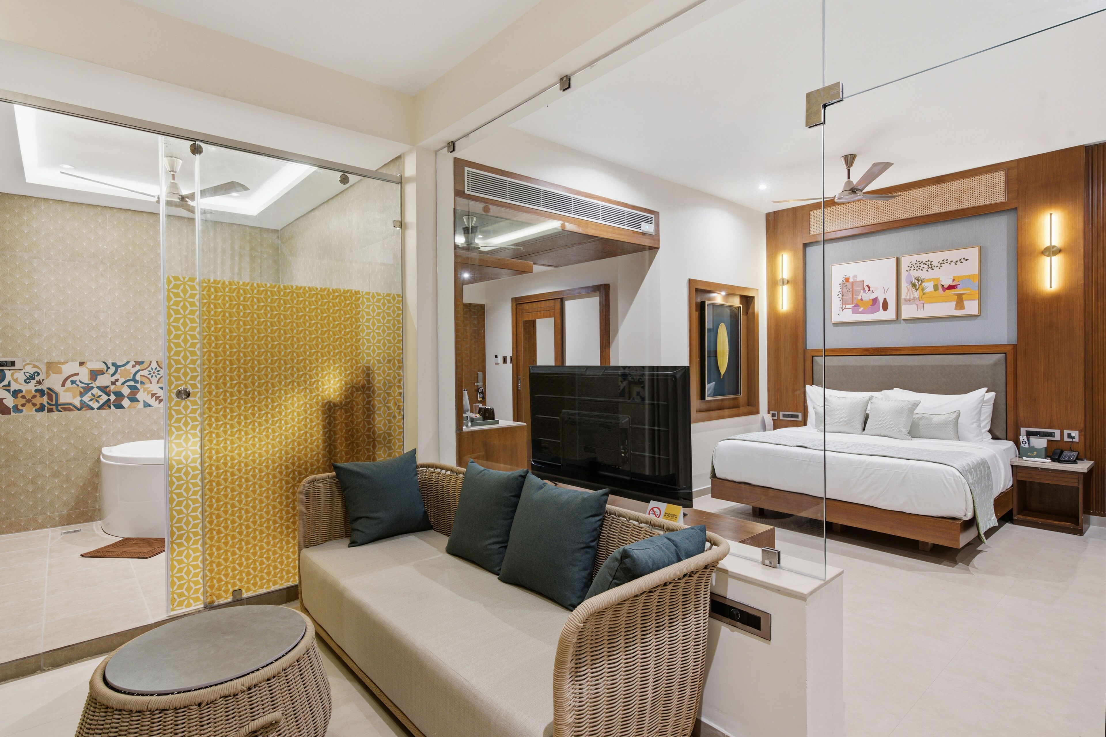 A hotel room with a bed, sofa, TV, and a bathroom with a shower and toilet.