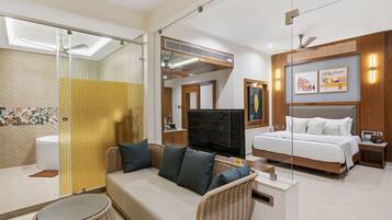 A hotel room with a bed, sofa, TV, and a bathroom with a shower and toilet.