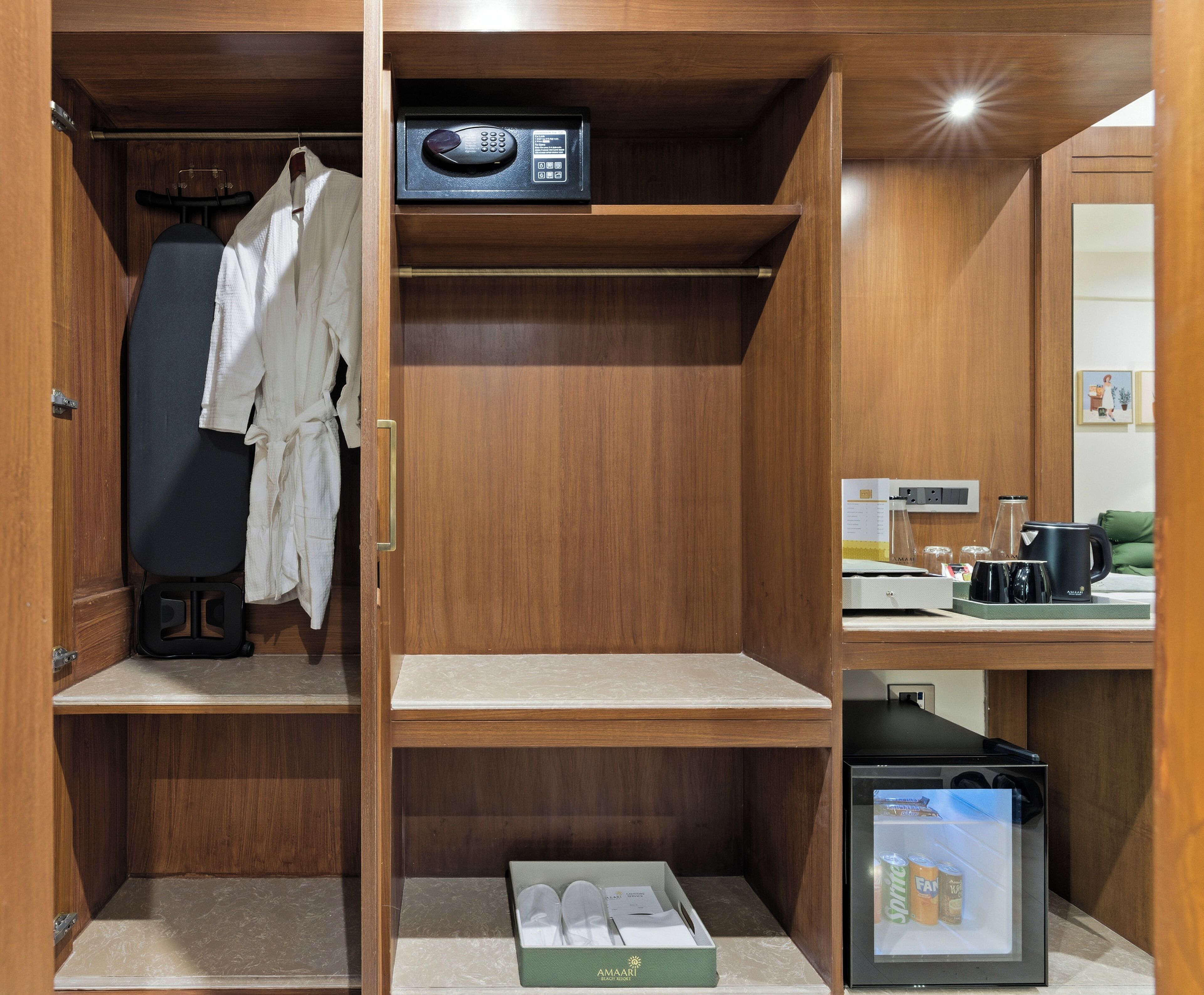A compact, well-organized room with a wooden wardrobe, a small refrigerator, and a coffee maker.