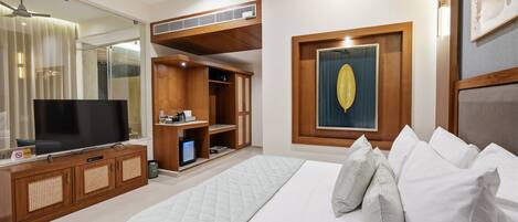 Habitación de hotel con cama, televisión, armario y un amplio ventanal.