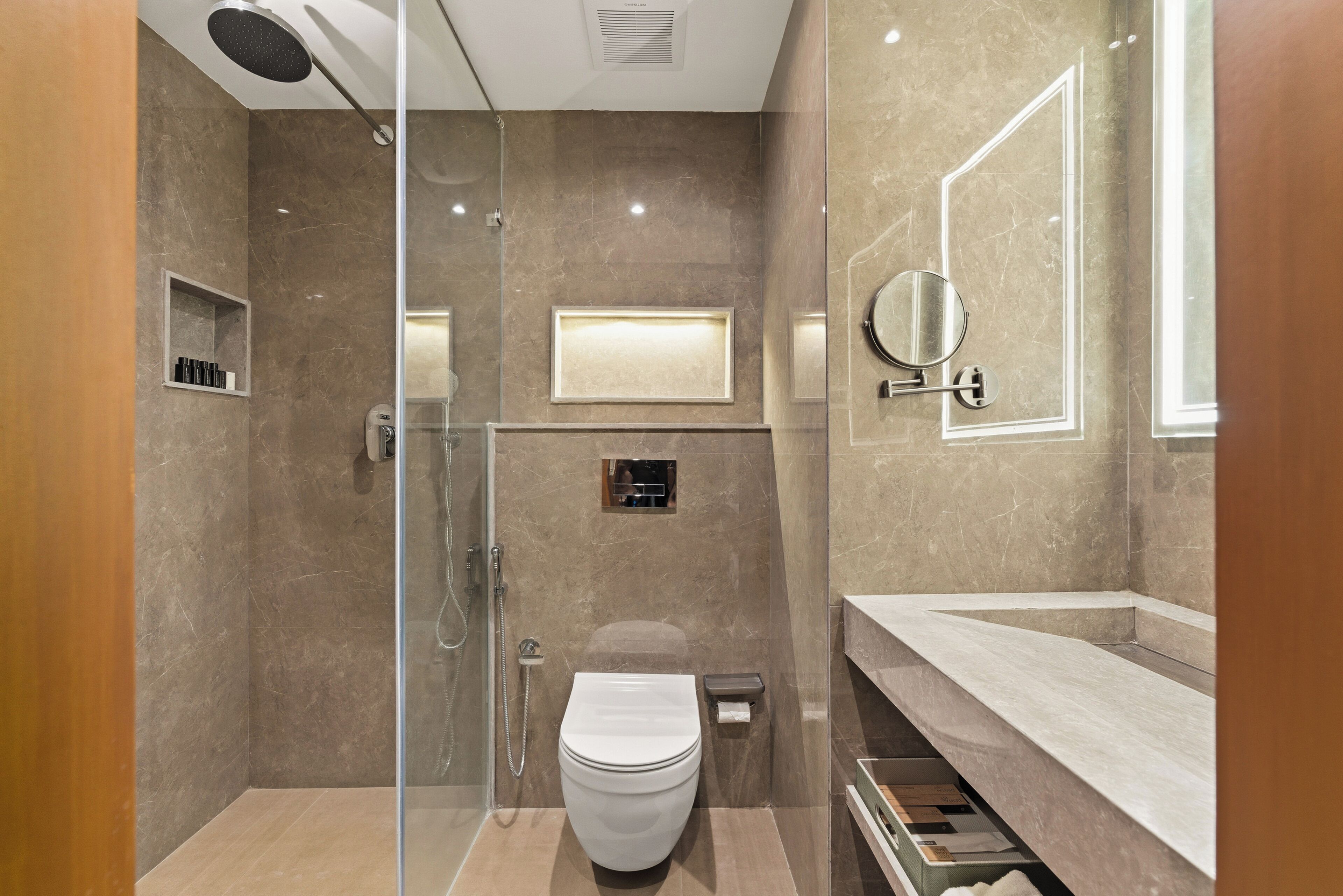 A modern bathroom with a glass-enclosed shower, a toilet, and a vanity with a mirror.