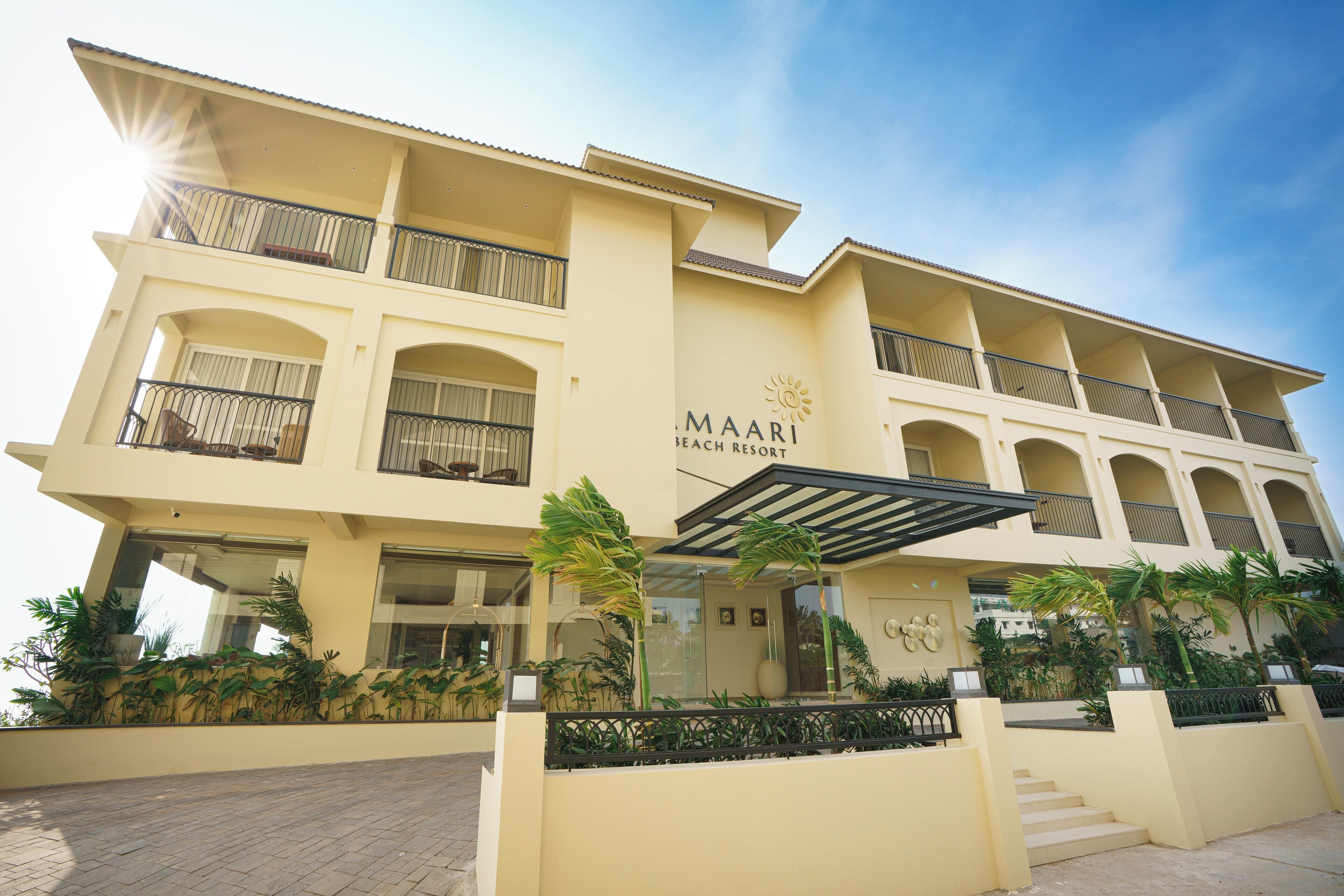 Un hôtel à plusieurs étages, doté de balcons, d’un emblème solaire et portant le nom de « MAARI Beach Resort ».