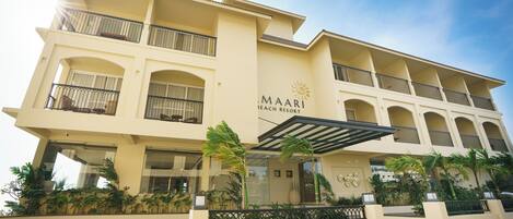 Un hôtel à plusieurs étages, doté de balcons, d’un emblème solaire et portant le nom de « MAARI Beach Resort ».