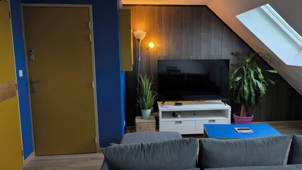 Una sala de estar moderna con televisión, un sofá, una mesa de centro y una planta en maceta.