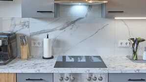 Una cocina moderna con horno empotrado, campana extractora de acero inoxidable y encimeras de mármol.