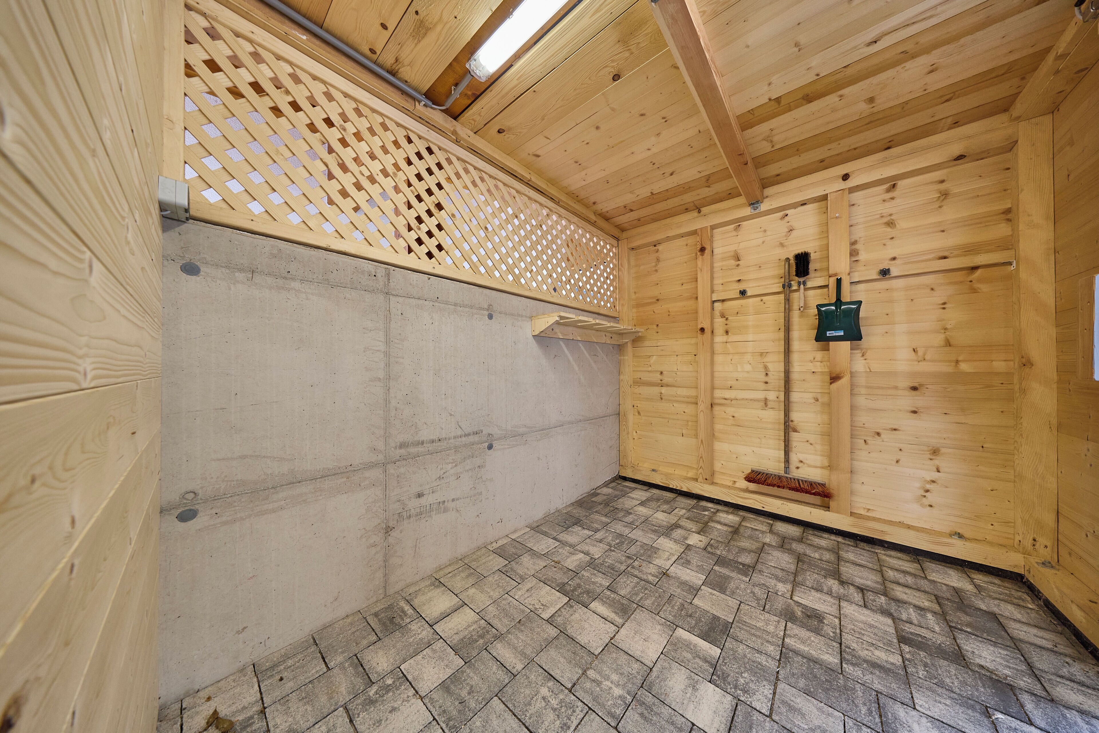 A wooden interior with a herringbone floor, a wooden door, and a metal gate.