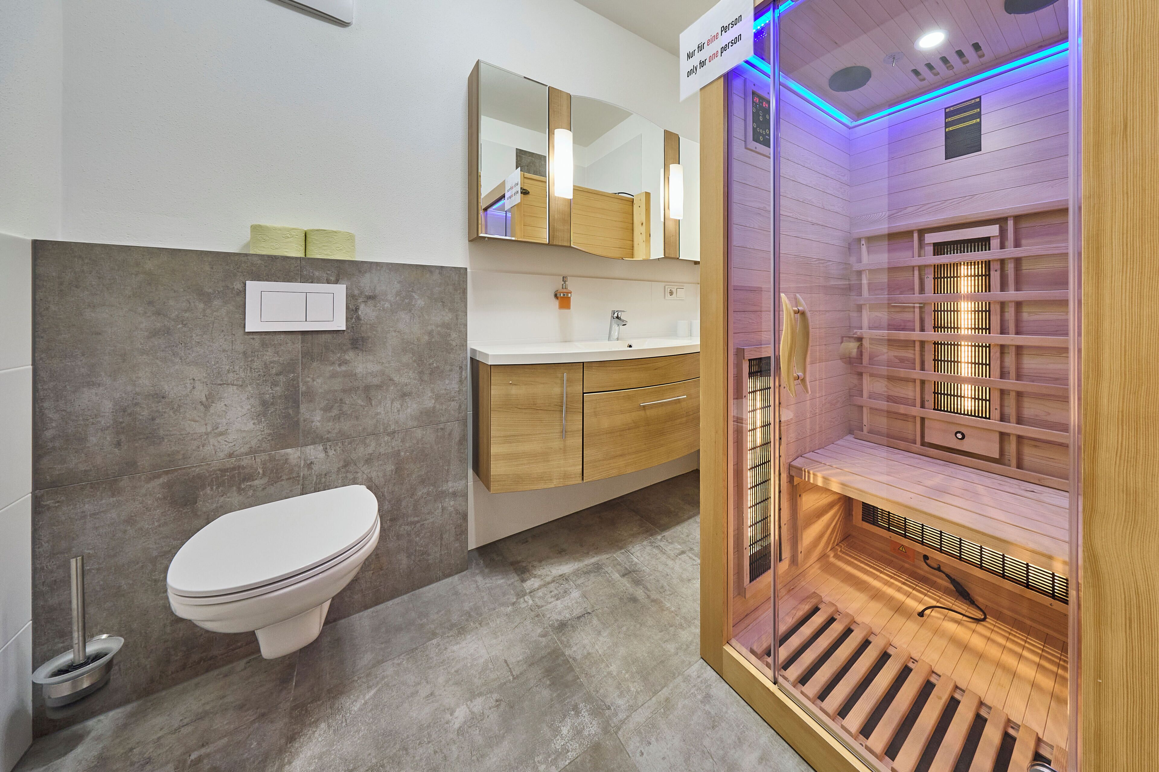 Een moderne badkamer met toilet, wastafel, spiegel en een stoomdouche.