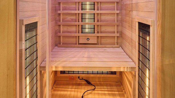 Una sauna con paredes de madera, un banco de listones e iluminación empotrada en el techo.