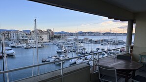 A balcony with a view of a marina filled with boats, a table, and chairs. - Cap Hermès, 4th floor with magnificent harbor view, sleeps 4, air conditioning, swimming pool, Wi-Fi, parking (Fréjus)