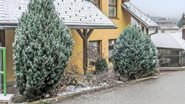Ein gelbes Haus mit Satteldach und Veranda.