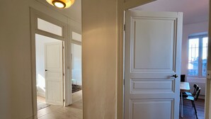 A hallway with a white door, wooden flooring, and a ceiling light fixture. - Chez MARIE - Central and Comfort (Valence)