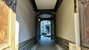 A narrow hallway with ornate wooden doors and a brick floor. - Chez MARIE - Central and Comfort (Valence)