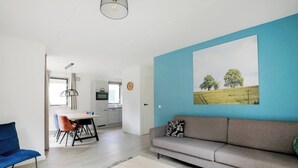 Un salon moderne avec un canapé gris, une table basse et un coin repas comprenant une table et des chaises.