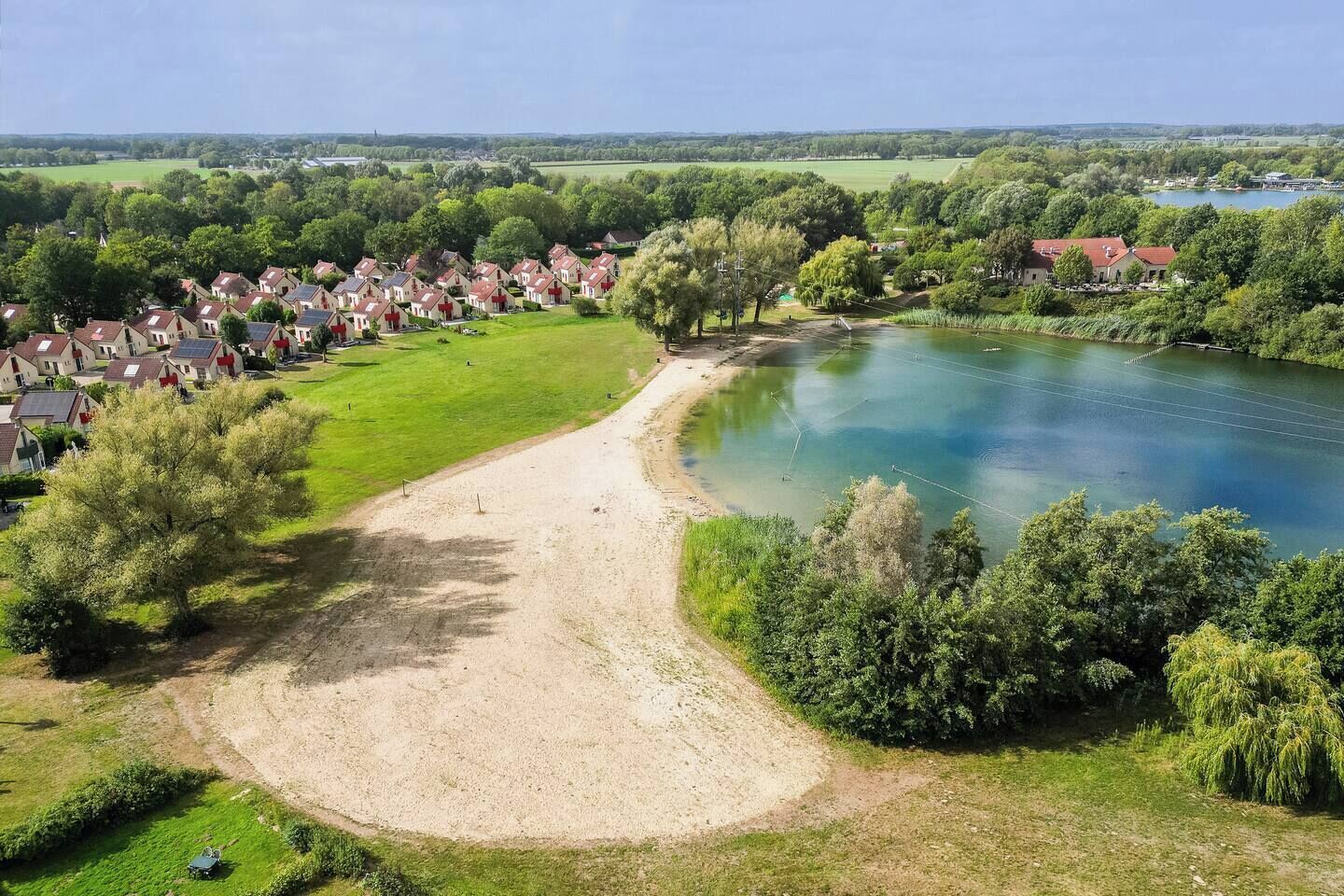 Un quartier résidentiel avec des maisons, une rivière et un sentier de terre.